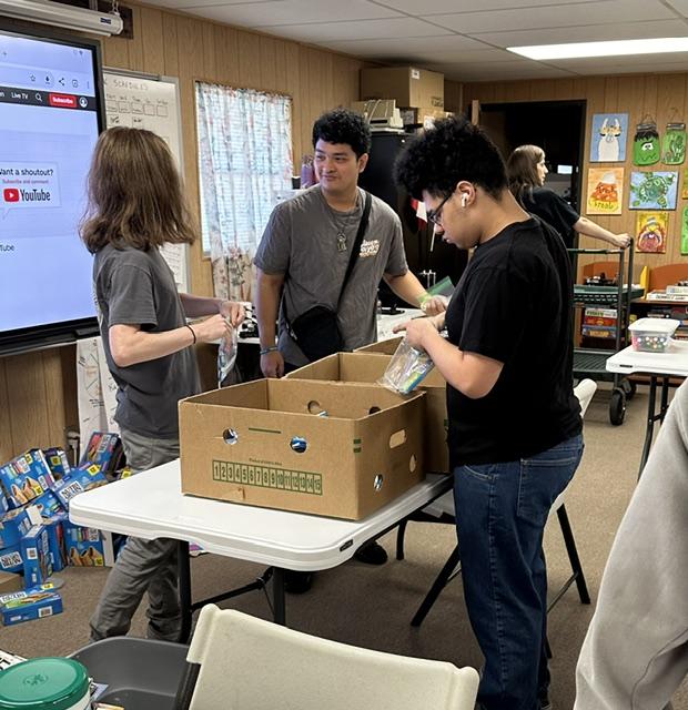 Young adults preparing food bags for Leander ISD families